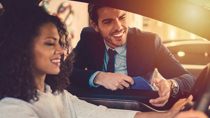 Salesman explaining the car to smiling woman.png1